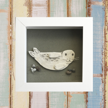 Load image into Gallery viewer, Photo of a picture of a seal pup made by artist Michelle Costello of Smartie Lids on the Beach. This picture is entirely made from the insole of a wellie boot and plastic rocks, all found on Cornish beaches!