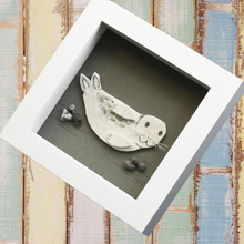 Load image into Gallery viewer, Photo of a picture of a seal pup made by artist Michelle Costello of Smartie Lids on the Beach. This picture is entirely made from the insole of a wellie boot and plastic rocks, all found on Cornish beaches!