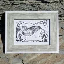 Load image into Gallery viewer, A photograph of a framed linocut of a seal called Arrowhead, made by printmaking artist Holly Dominique
