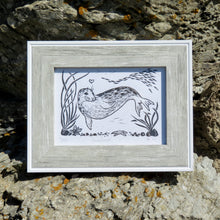 Load image into Gallery viewer, A photograph of a framed linocut of a seal called Arrowhead, made by printmaking artist Holly Dominique